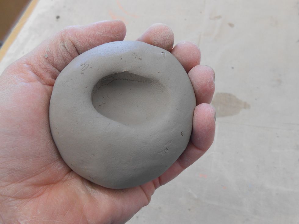 start making your first pinch pot by holding the ball of clay in your non-dominate hand and pressing your thumb in with your dominate hand