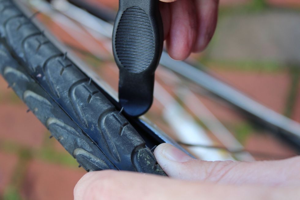 Start on the opposite side of the tire from the valve stem and work the first of two tire levers into the seam, separating the tire from the tire rim.