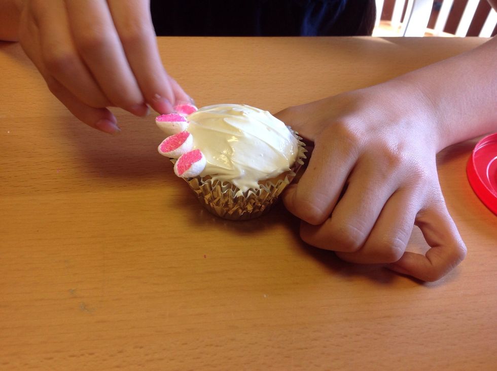 Start putting the marshmallows on the outside. Put the flat side on the frosting so it looks like petals.