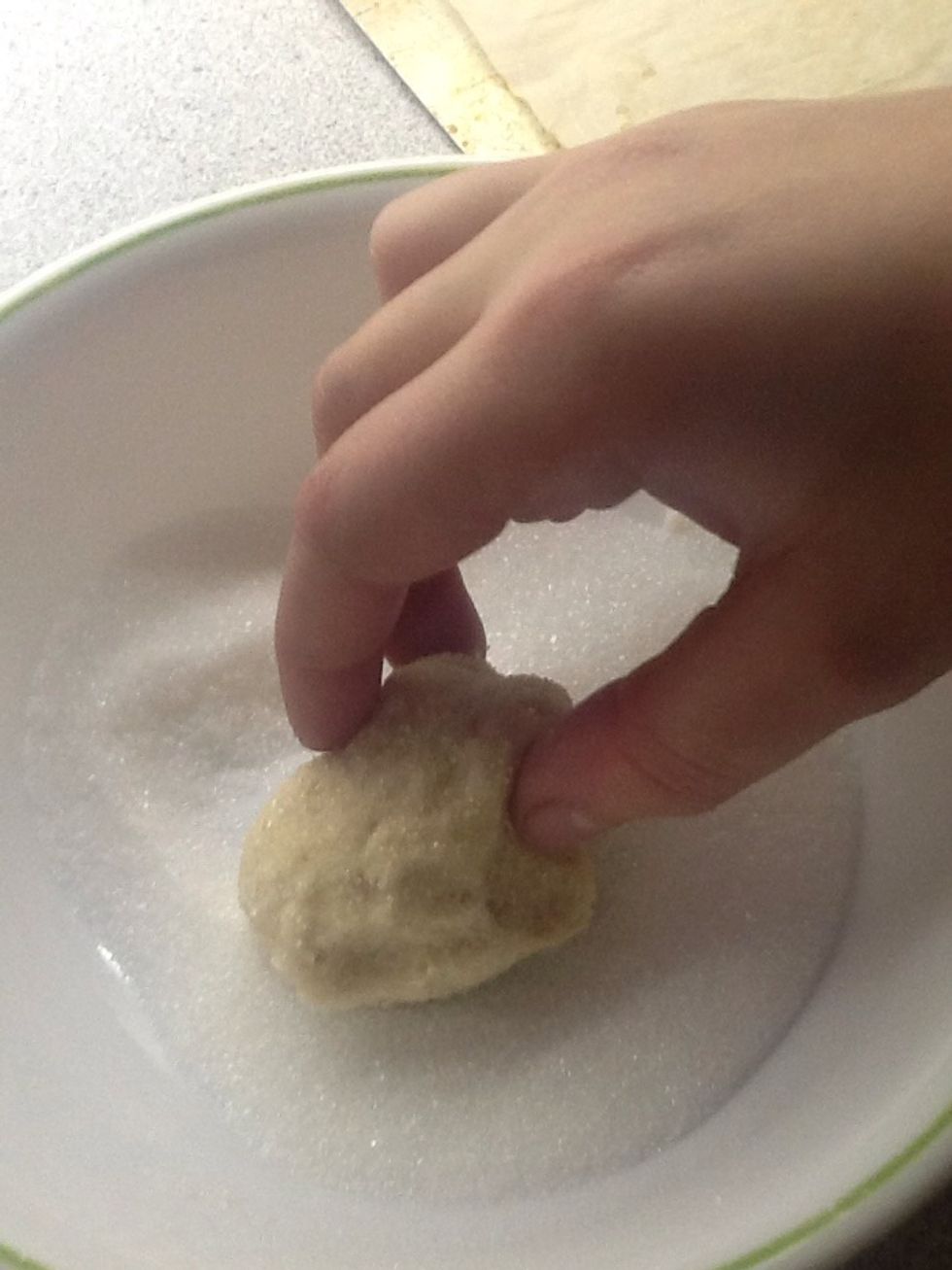 Start rolling your cookie balls in the sugar.