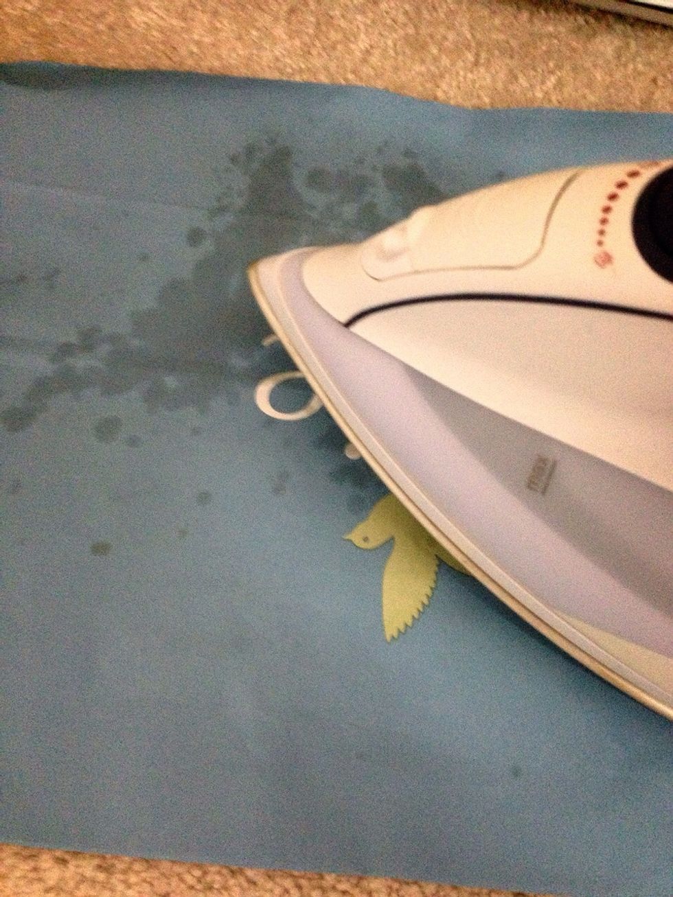 Start to iron over it, using the direct heat to melt the wax off of the carpet onto the paper! The paper absorbs the wax very well. After you use up a strip, place it onto your handy towel.