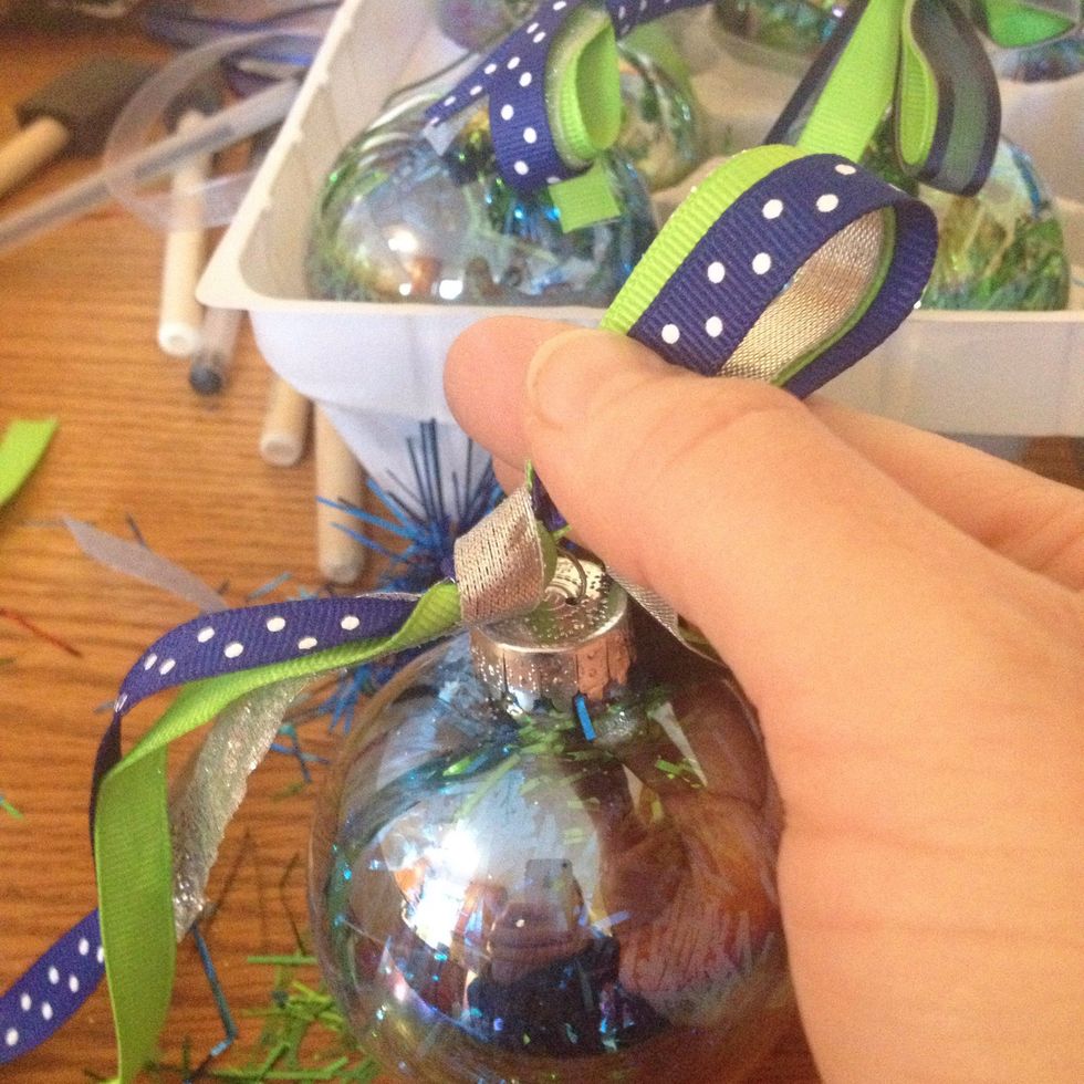 Start tying a bow on the ornament like this.