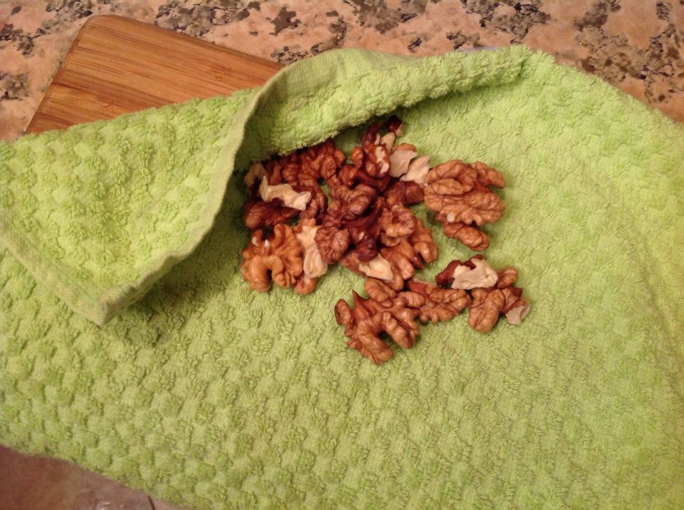 Start with the walnuts. You need to crumble it. As I was going to pound it, I put a towel on my cutting board and placed the walnuts there to avoid its crumbs of flying away