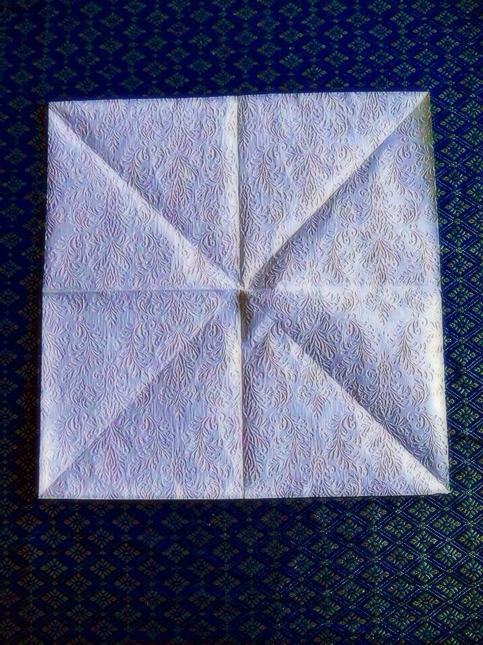 Start with unfolded napkin. Color that you want your petals to be that side gas to face the table