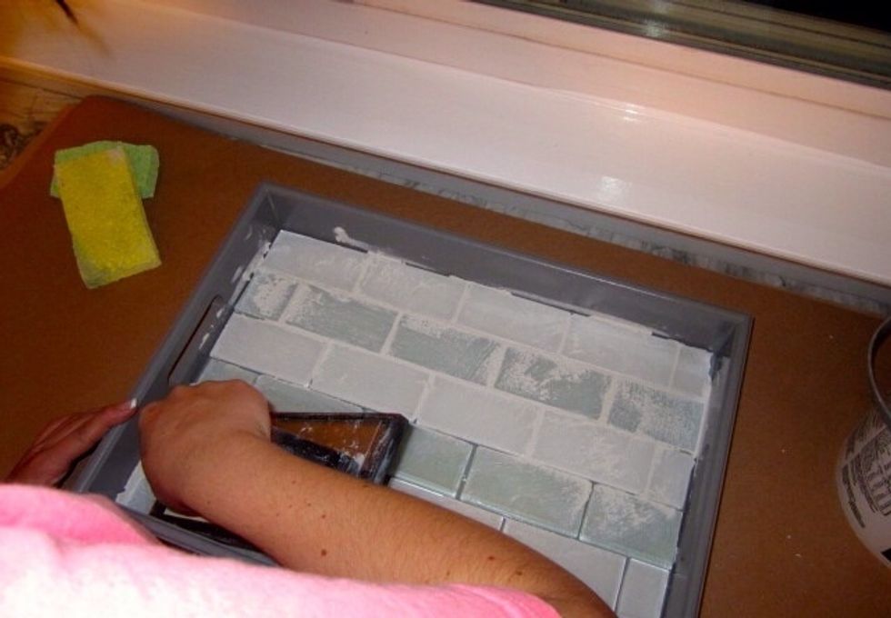 Start working the grout in and spread it across the entire tray.