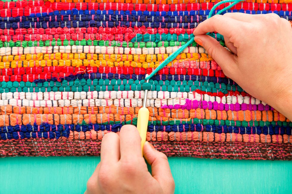 Starting at the base of the rug, tuck the crochet hook through one of the loops in the rug, hook the top loop of the yarn on the crochet hook and pull the loop through.