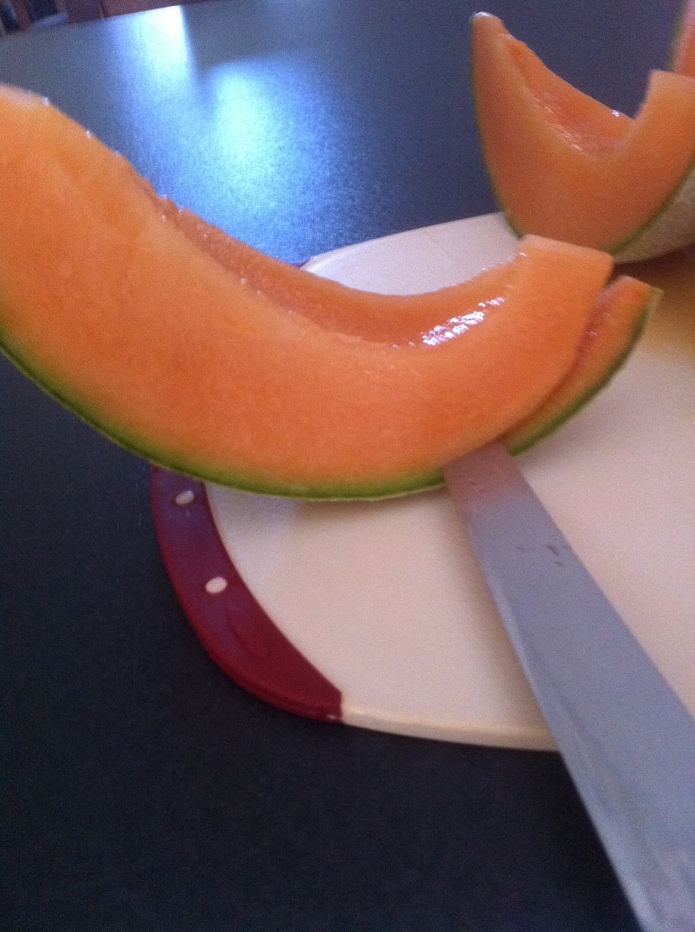 Starting at the end cut into melon slice staying close to the peel as possible. About half way through take your knife out and turn the melon and start again until you meet up with your previous cut.