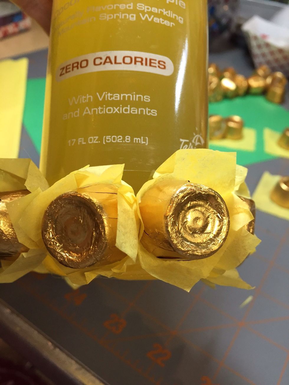 Starting on the bottom of the bottle, begin to glue candies to bottle.