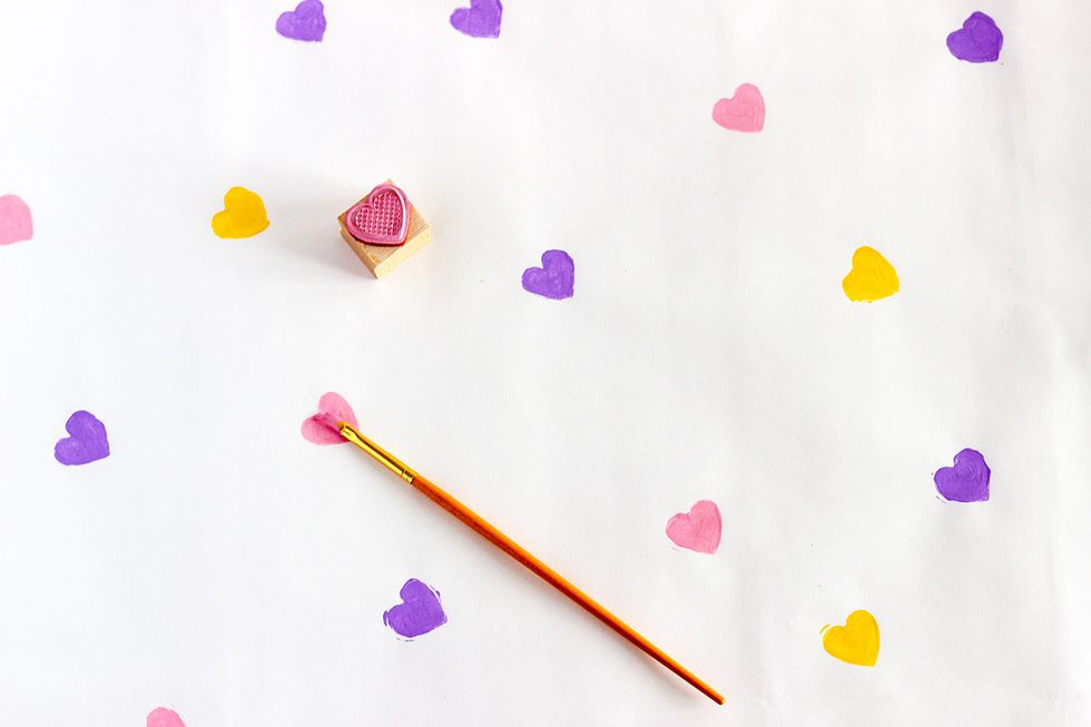 Starting with one colour at a time, dip your heart stamp into the paint and stamp the craft paper. I used the paint brush to fill in the hearts in case some paint was missing.