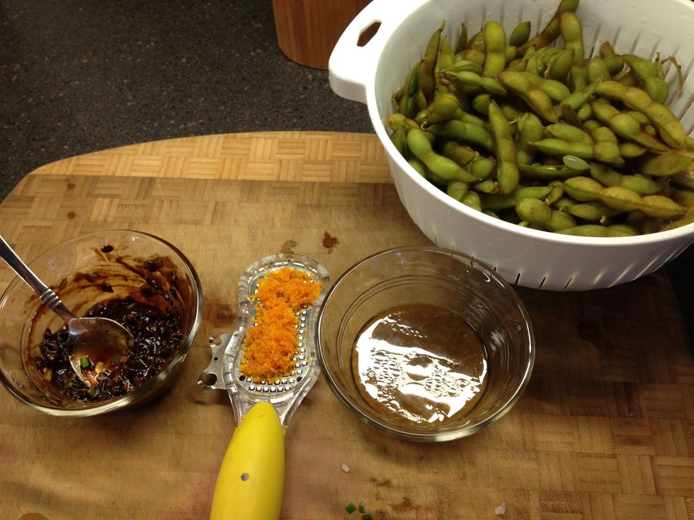 Steam frozen edamame about 3 min in salted water. In one bowl add black bean sauce, ginger and green onions. In the other combine oj, sesame oil and soy sauce.