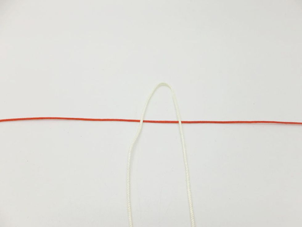 Step 1: Cut two pieces of red cords at least 50cm long. Fold the yellowish cord in half. Then take one of red cord under the yellowish cord
