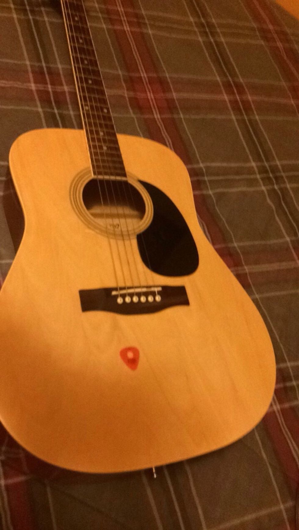 Step 1: get a guitar and guitar pick, make sure it is tuned in standard tuning Picture:Guitar laying down next to a guitar pick