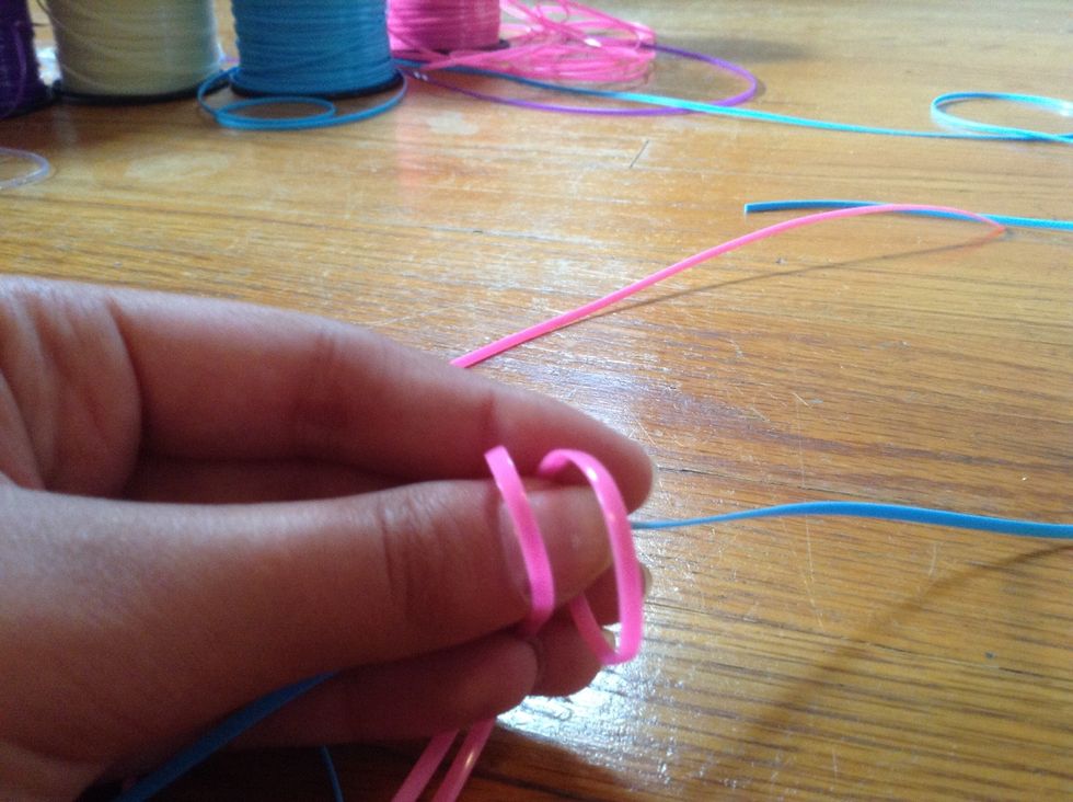 Step 1: loop the pink string from one side to the other. Do this with both pink strings.