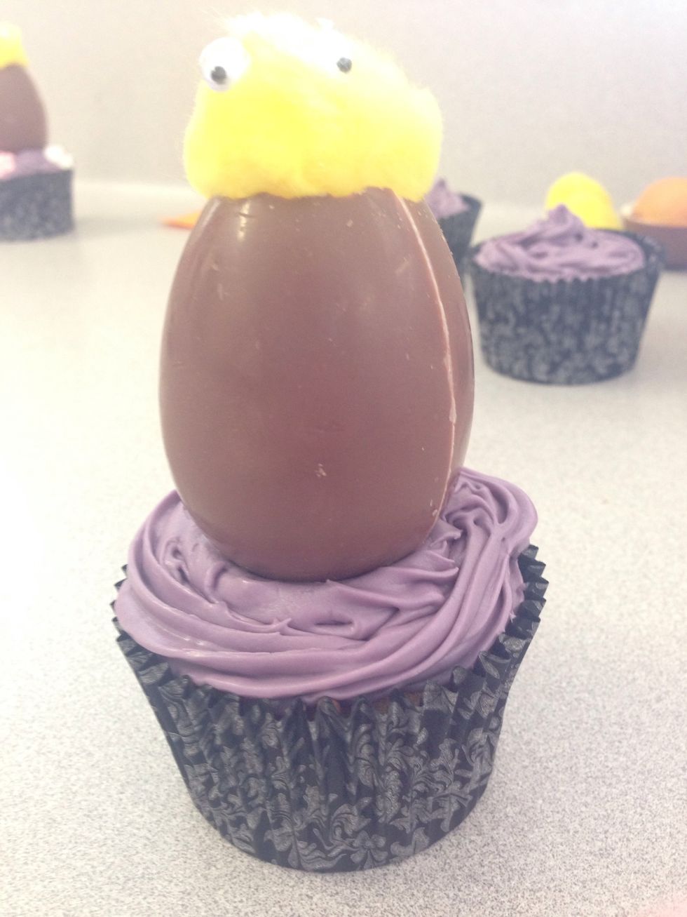 Step 10. Please the chocolate egg on top of the cupcake making sure it is straight and can sit by itself. You may need to keep moving it around in the icing until it Will stand on it's own.