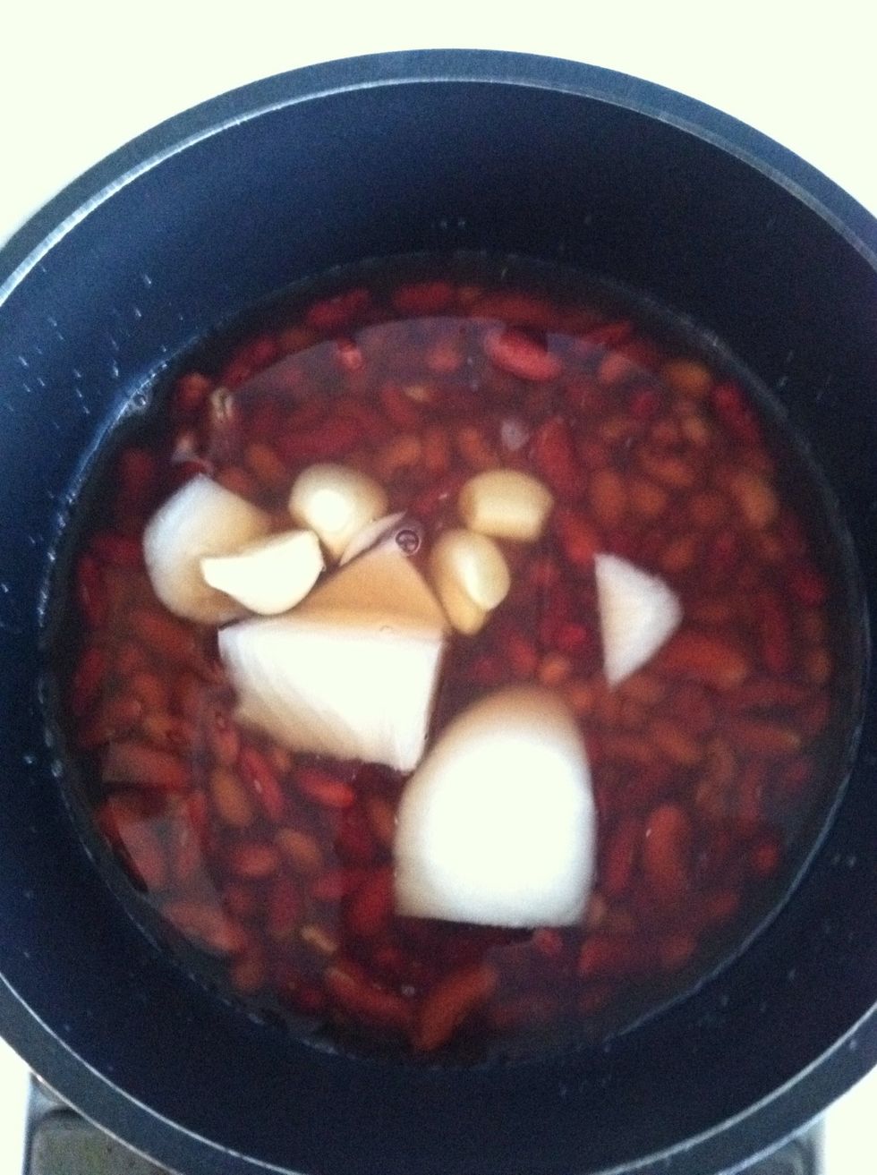 Step 2. Cut 1/2 a white onion Into quarter pieces, add to the soaked kidneys beans and place them on the stove. Cook over medium heat. Stir occasionally, place lid over them until beans are soft.