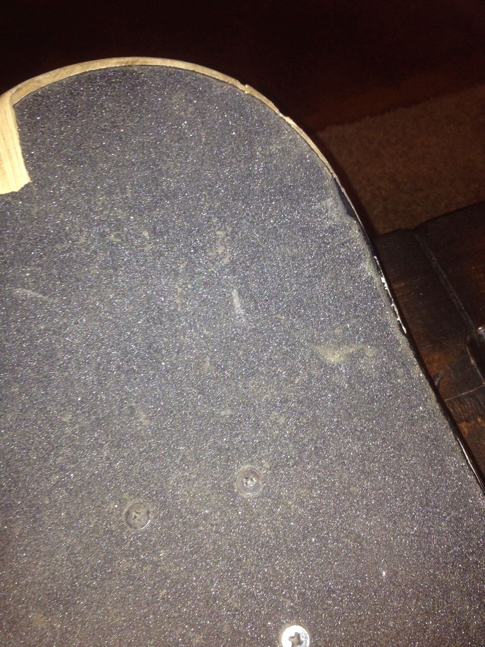 Step 2- Lay the skateboard face down. Place the grip on the top of the board, sticky side down and make sure there are no air bubbles. Cut off the excess grip tape hanging off the side of the deck.