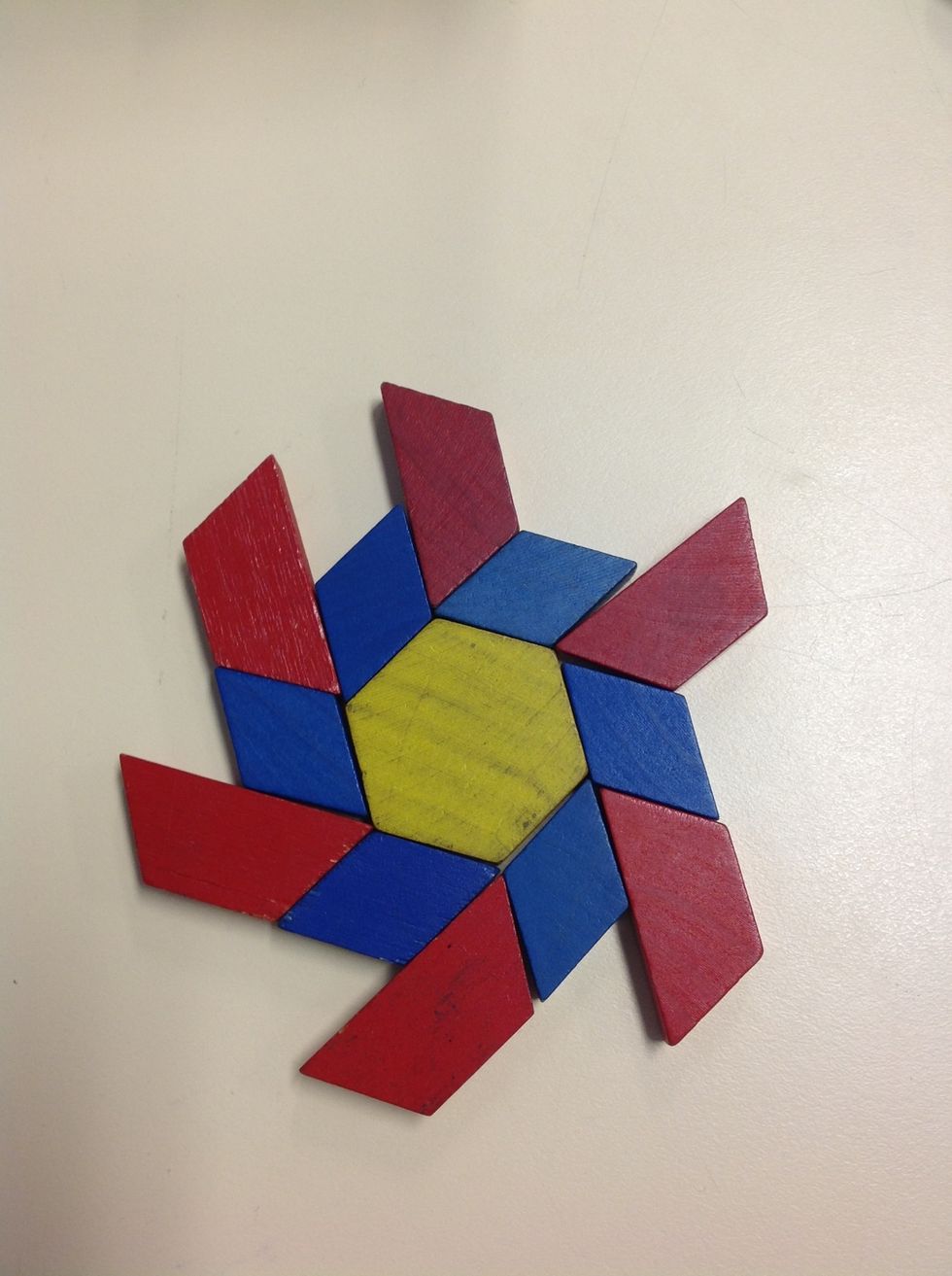 Step 3: Continue creating the pattern by placing coloured blocks of different shapes around the central shape.