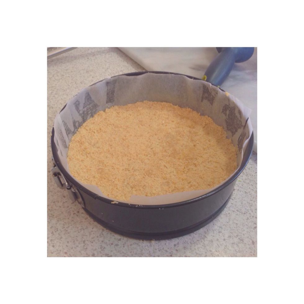Step 4. Line a 20cm circle tin with baking paper, then press the biscuit mixture, making a consistent base. Then put in the fridge.