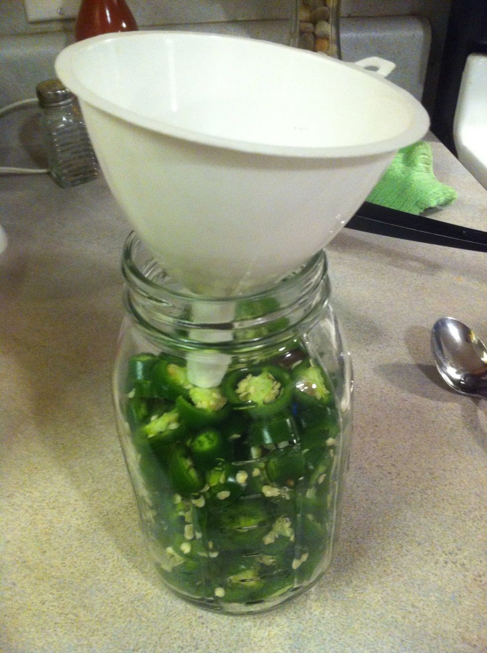Step 4: Using a funnel , pour the vinegar and salt mixture into the mason jar over the jalepenos