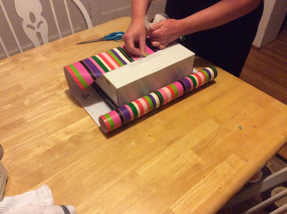 Step 5: Tape the sides of your wrapping paper down onto the present and repeat this step on the other half of the paper.