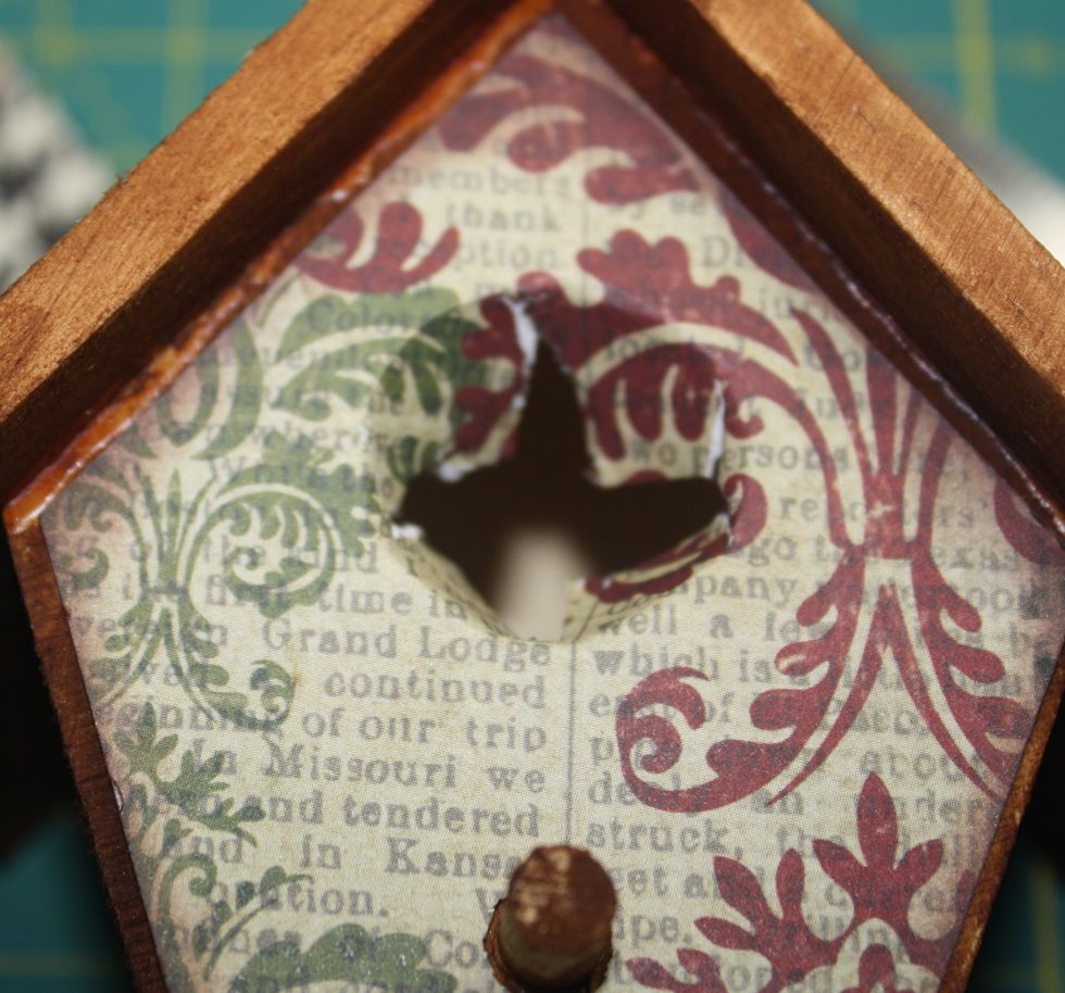 Step Four: Lay the paper on the birdhouse. Poke a small hole in the center of the opening.  Then use a small scissors to make cuts to the edge of the opening.