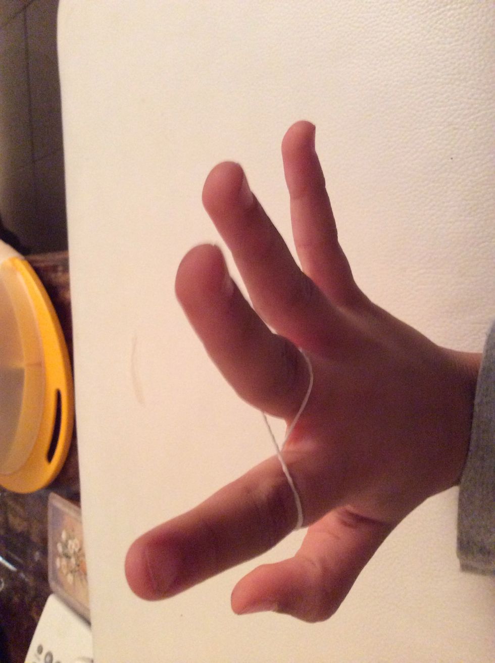 Step one, first take one rubber band and put it on your pointer finger and curve it then put it on your tall finger. It should look like the number eight. 8\u20e3