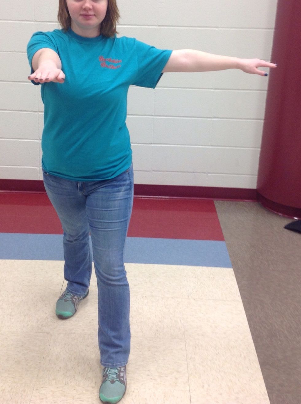 Step to the front with your left foot, make sure all your weight is on this foot. Leave your right foot where it is, put your right arm in a T position and your left arm straight out in front of you.