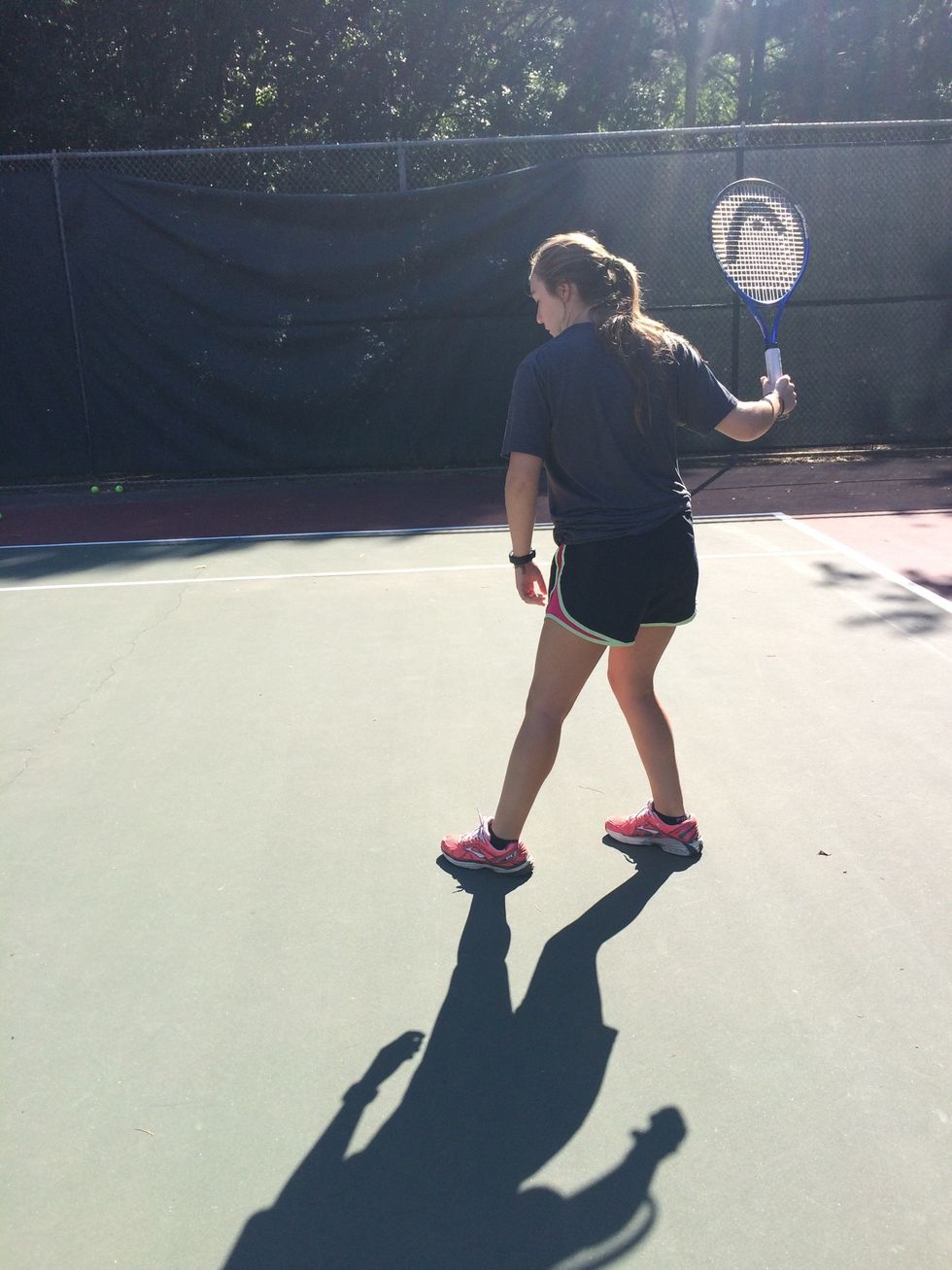 Step with non-dominant foot and raise racket behind body.