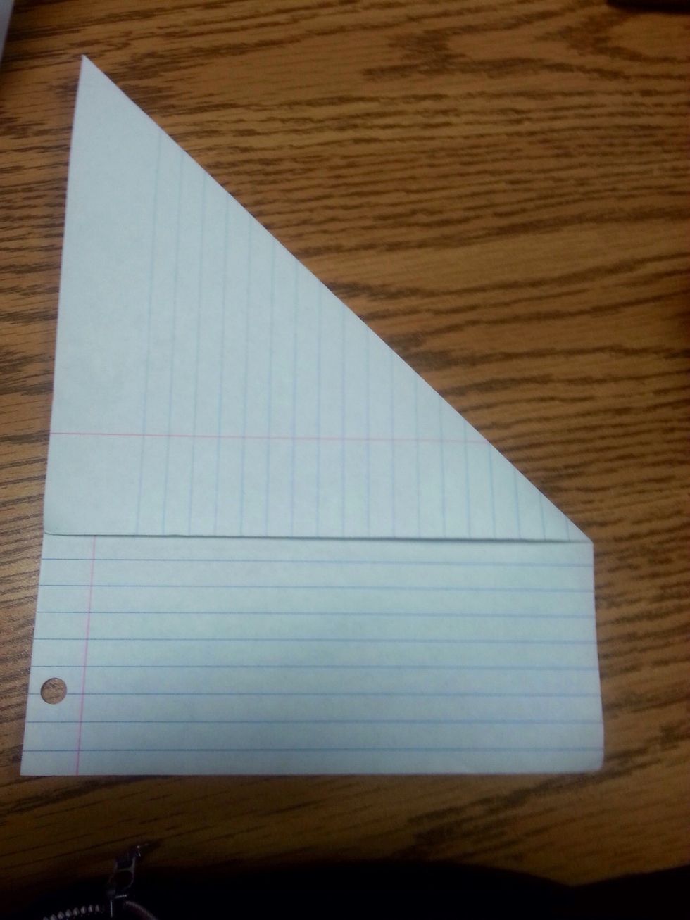Step2: take your paper from the right hand corner and fold it to the other side so it makes a triangle with some paper left at the bottom