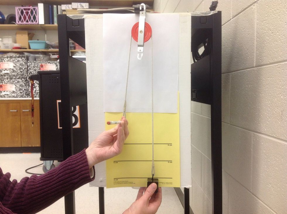 Stick a pencil through the loop at the effort.   Adjust the pencil up or down until the top edge of the load is right on one of the starting lines that read "0 cm."