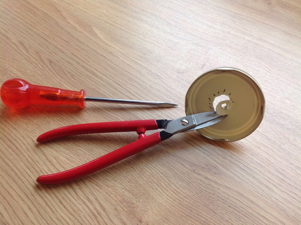 Stick ett h\u00e5l i mitten p\u00e5 locket med en syl och klipp sen upp h\u00e5let lite st\u00f6rre med en guldsmedsax.