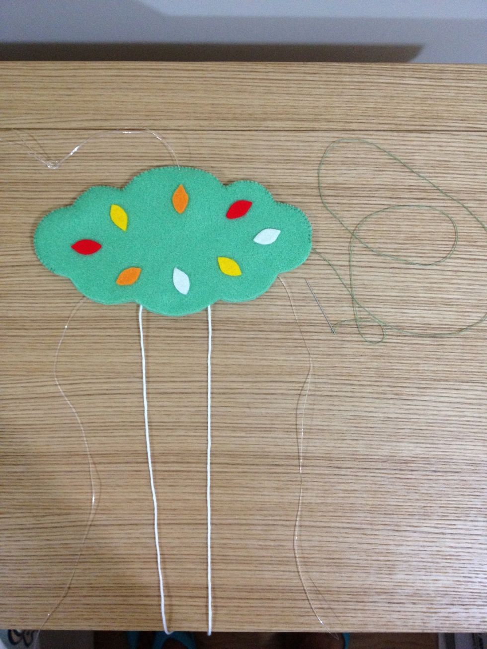 Stick pieces of leaves, in different colors, on both sides of the tree. Place both fishing lines and white strings inside the tree. Sew up and stuffed the tree!