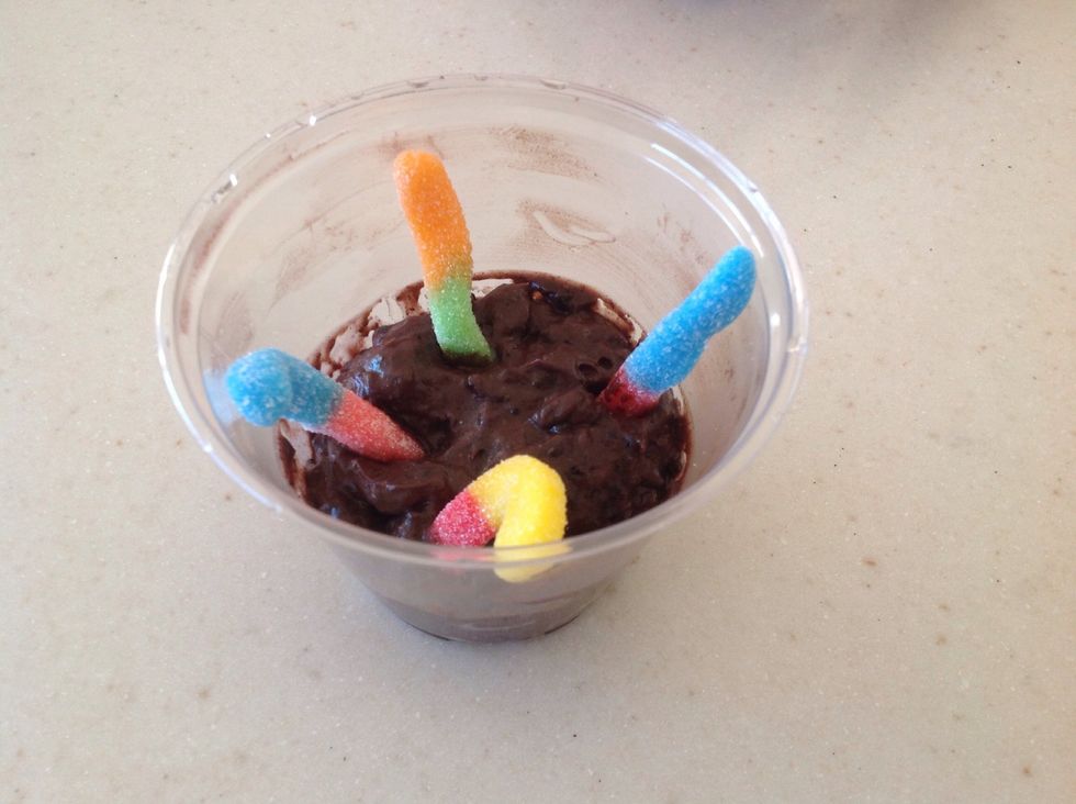 Stick the gummy worms in the pudding so that half of each worm is embedded in the mud, or pudding.