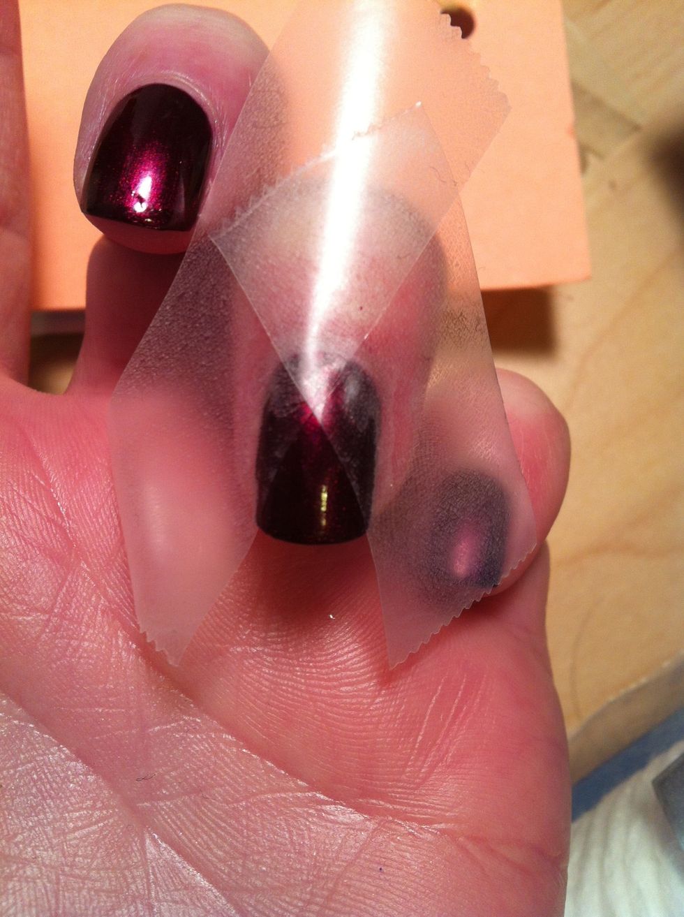 Stick two pieces of scotch tape to your arm (to dull the adhesive) then tape off your nail so a triangle of polish is showing.