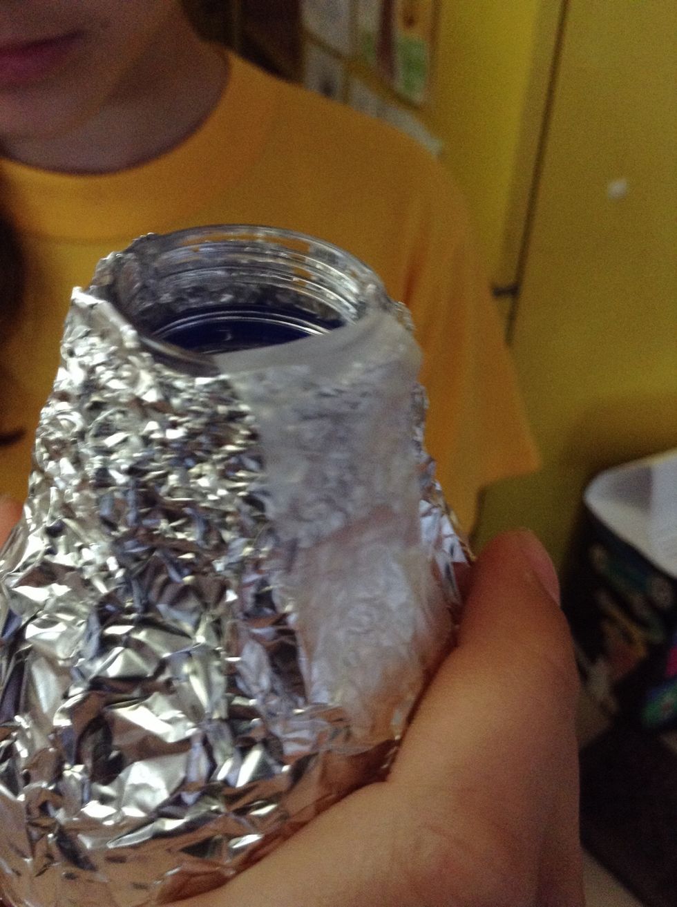 Sticky tape the foil to the small end of the bottle.