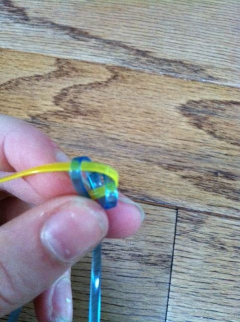 Still holding on to the loops carefully thread the yellow lanyard over the first blue loop and under the second one.