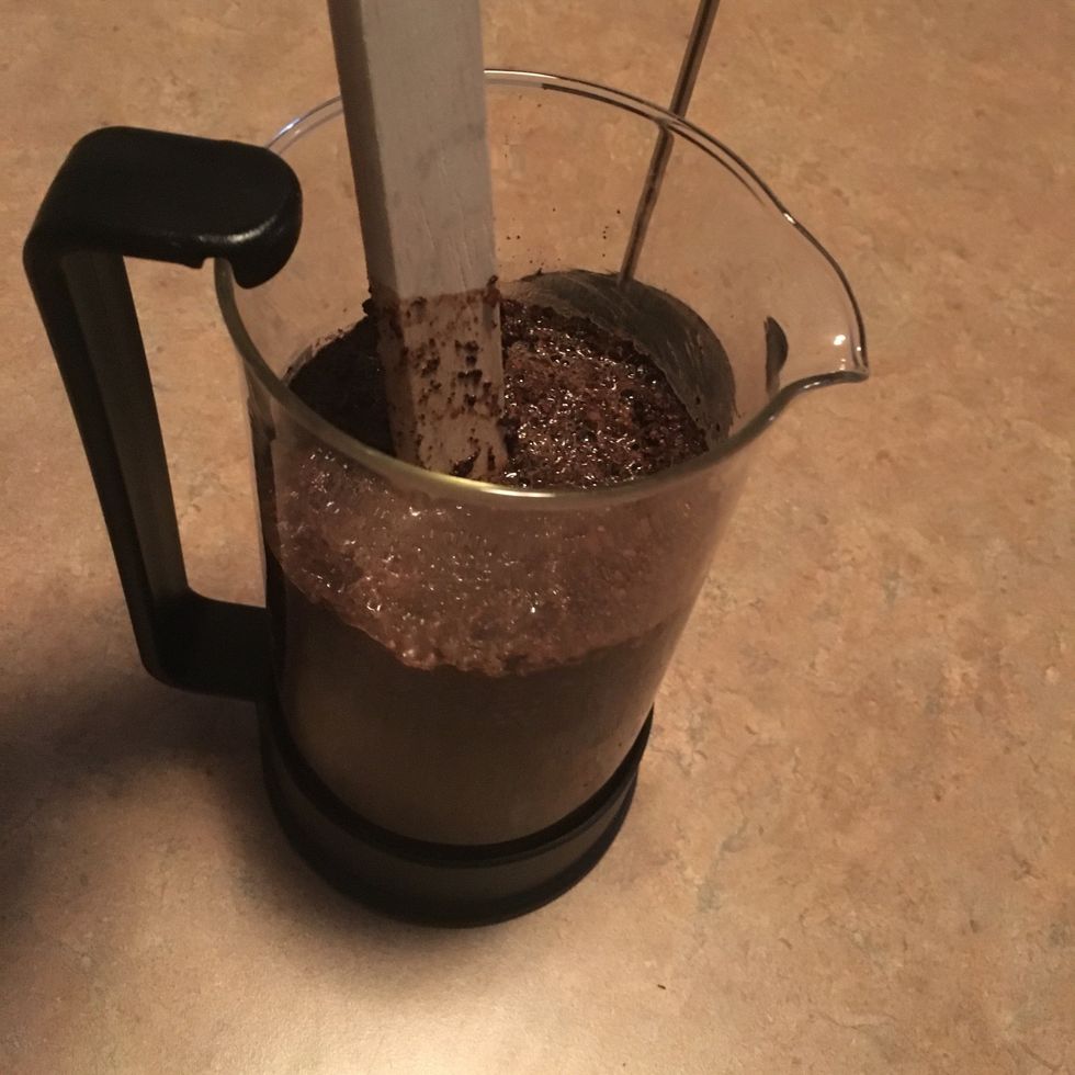 Stir grounds into water with wooden spoon, breaking up any clumps