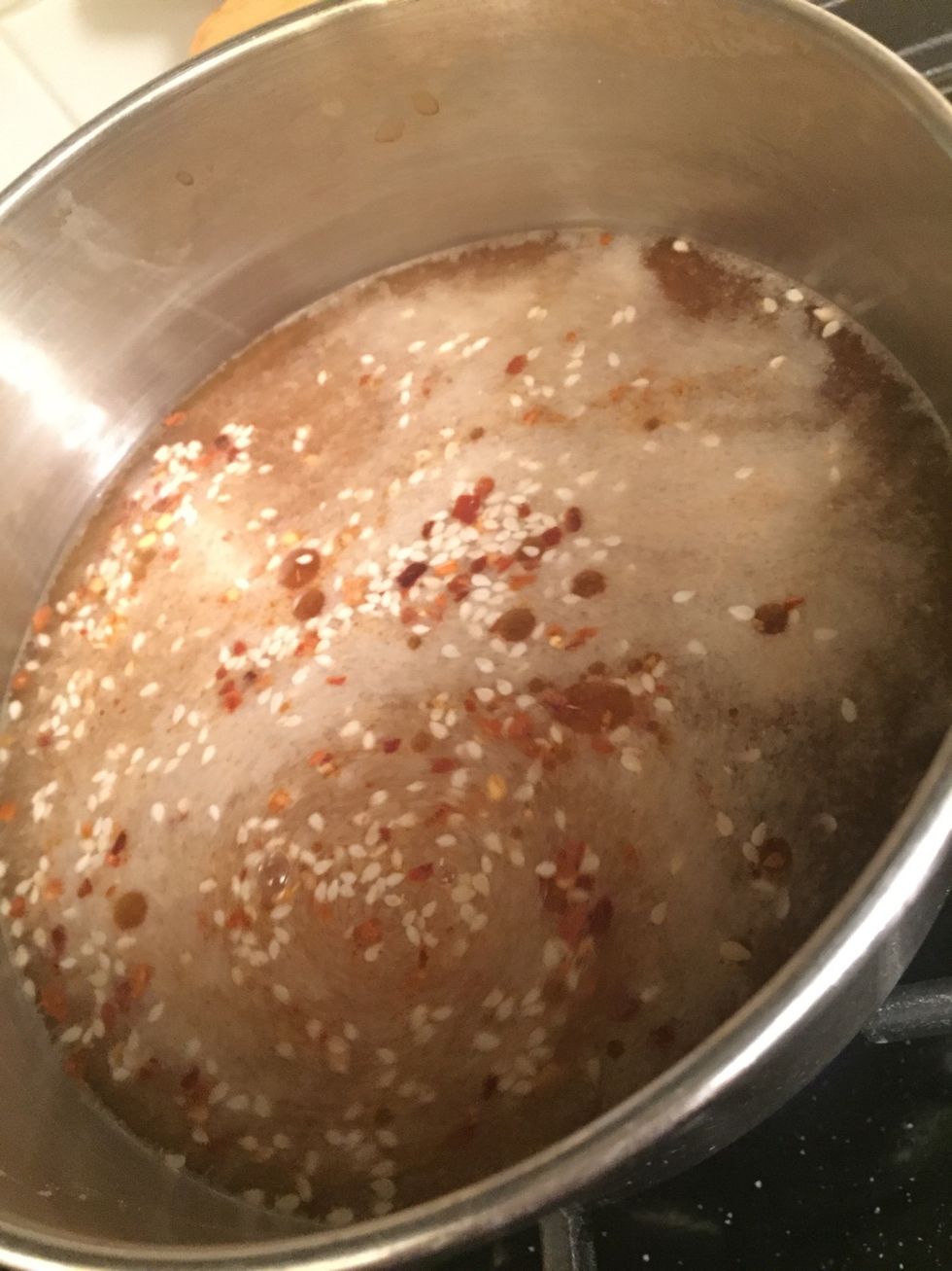 Stir in your chilli flakes, sesame seeds, garlic, onion, cayenne & ginger powder, and sriracha sauce, lime, and salt and pepper.