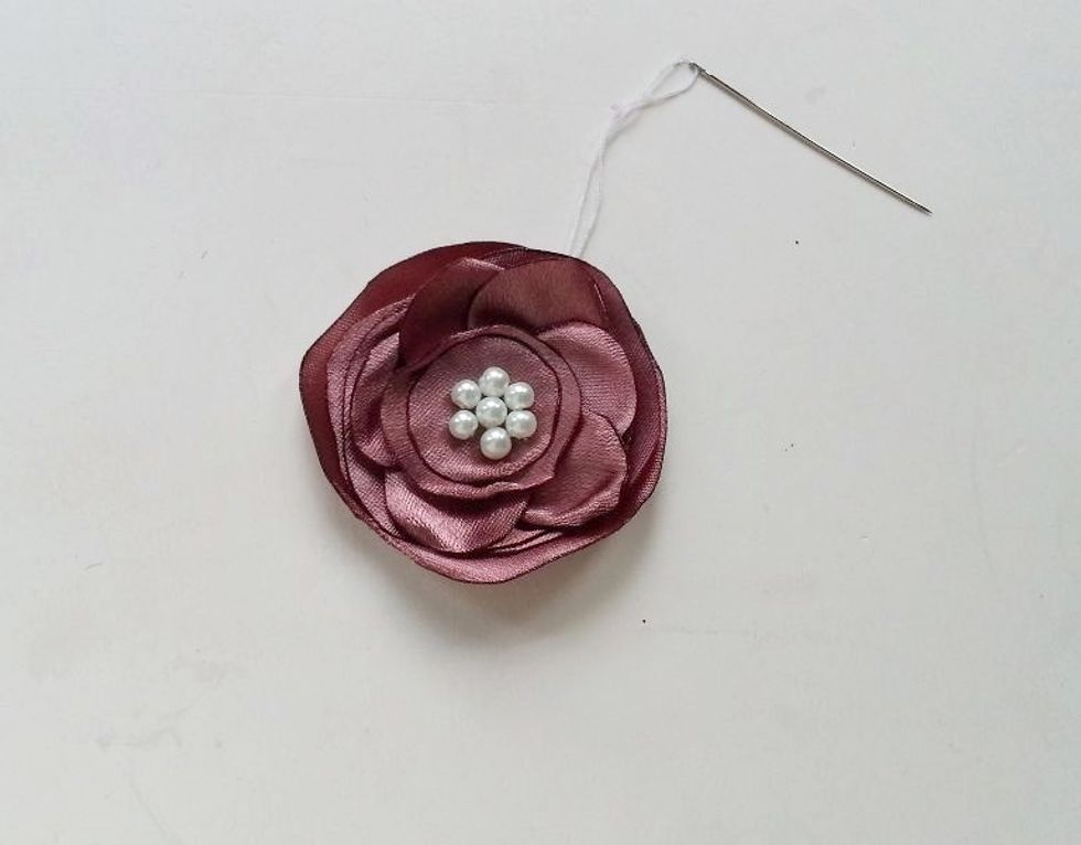 Stitch the center and meanwhile attach the beads on the center. After attaching beads simply draw the needle to the back, tie a knot and cut off extra thread.