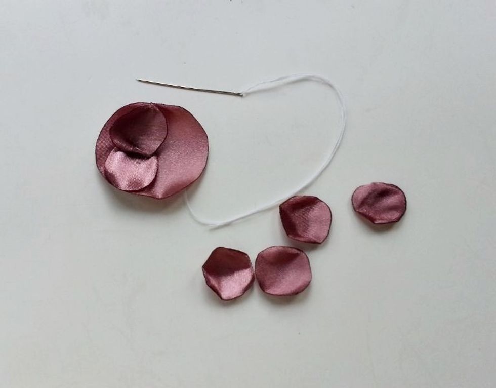 Stitch the petal with the smallest base piece at a side. Place another petals beside the first petal by slightly overlapping it and then stitch that one as well.