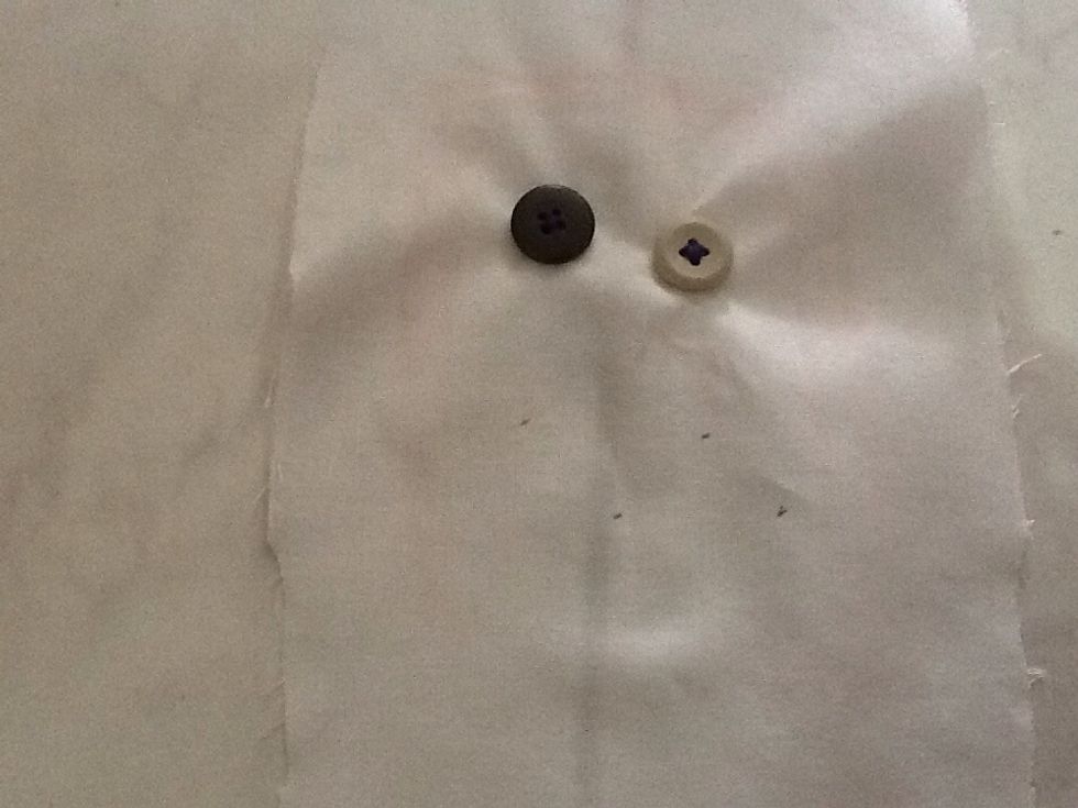 Stitch the second button onto the fabric