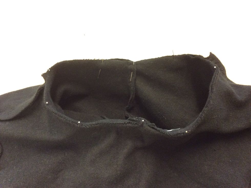 Stoppa ner luvan i halsringningen s\u00e5 att tygerna ligger r\u00e4ta mot r\u00e4ta. N\u00e5la och se till att mittbaks\u00f6mmen m\u00f6ter n\u00e5len bak och omlottn\u00e5len n\u00e5len fram i halsringningen.