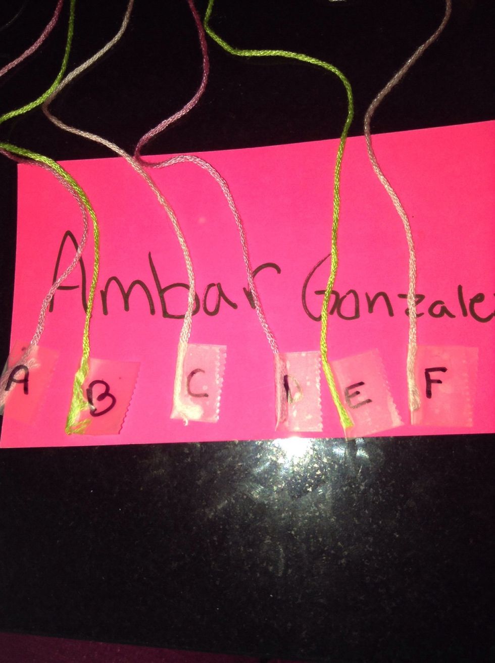 Straighten and separate strings. Label strings A through F attach a piece of tape at the end of the strings on the bottom part of the bracelet and with a marker write the letters A through F.