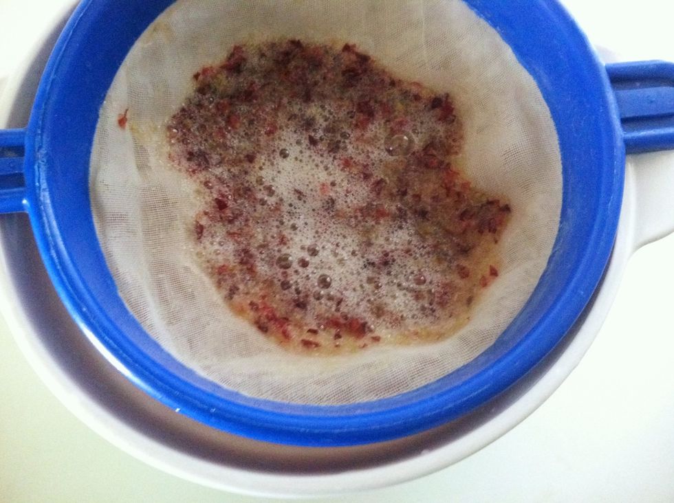 Strain in a sieve with extremely small holes or use a coffee filter.