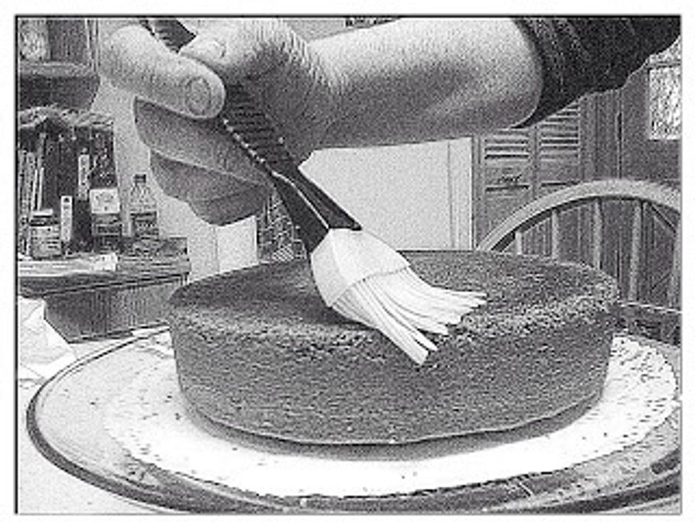 Strain the mixture through a fine sieve and pour it into a 2 cup glass measure.  Using about 1/3 cup of this syrup, paint the top of the cake with it. Always let the syrup sink in before you add more.