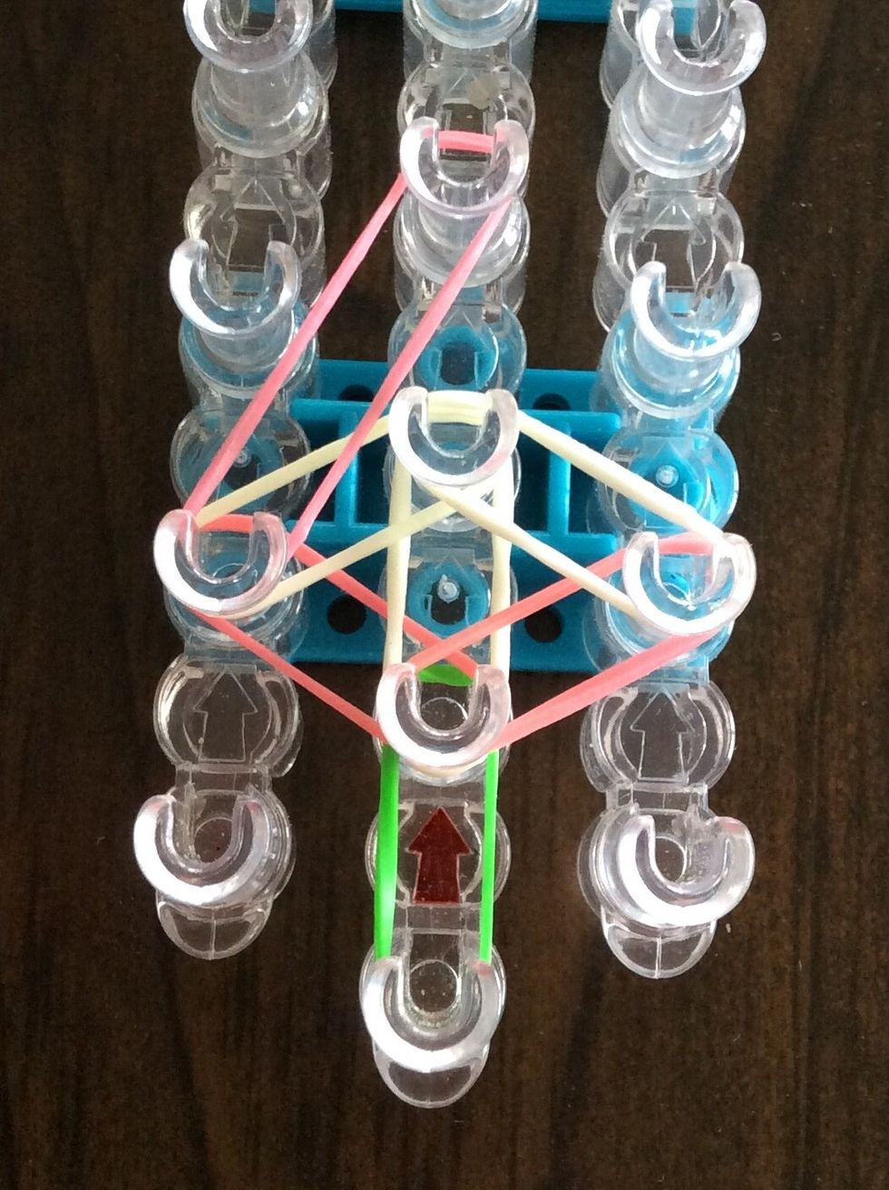 Stretch a pink band from the second left peg to the fourth middle peg.