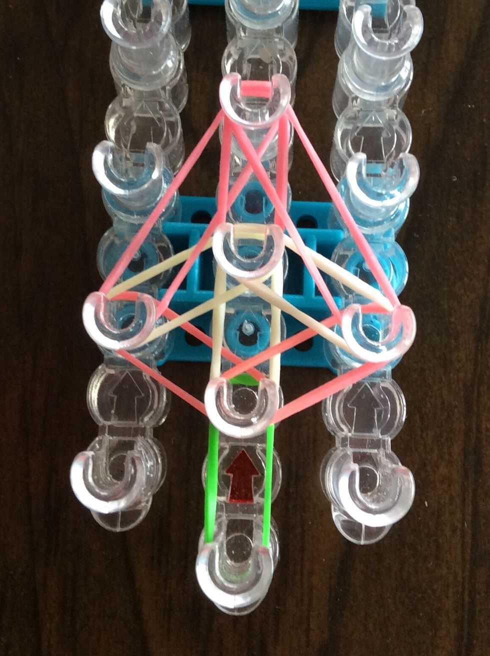Stretch a pink band from the second right peg to the fourth middle peg.