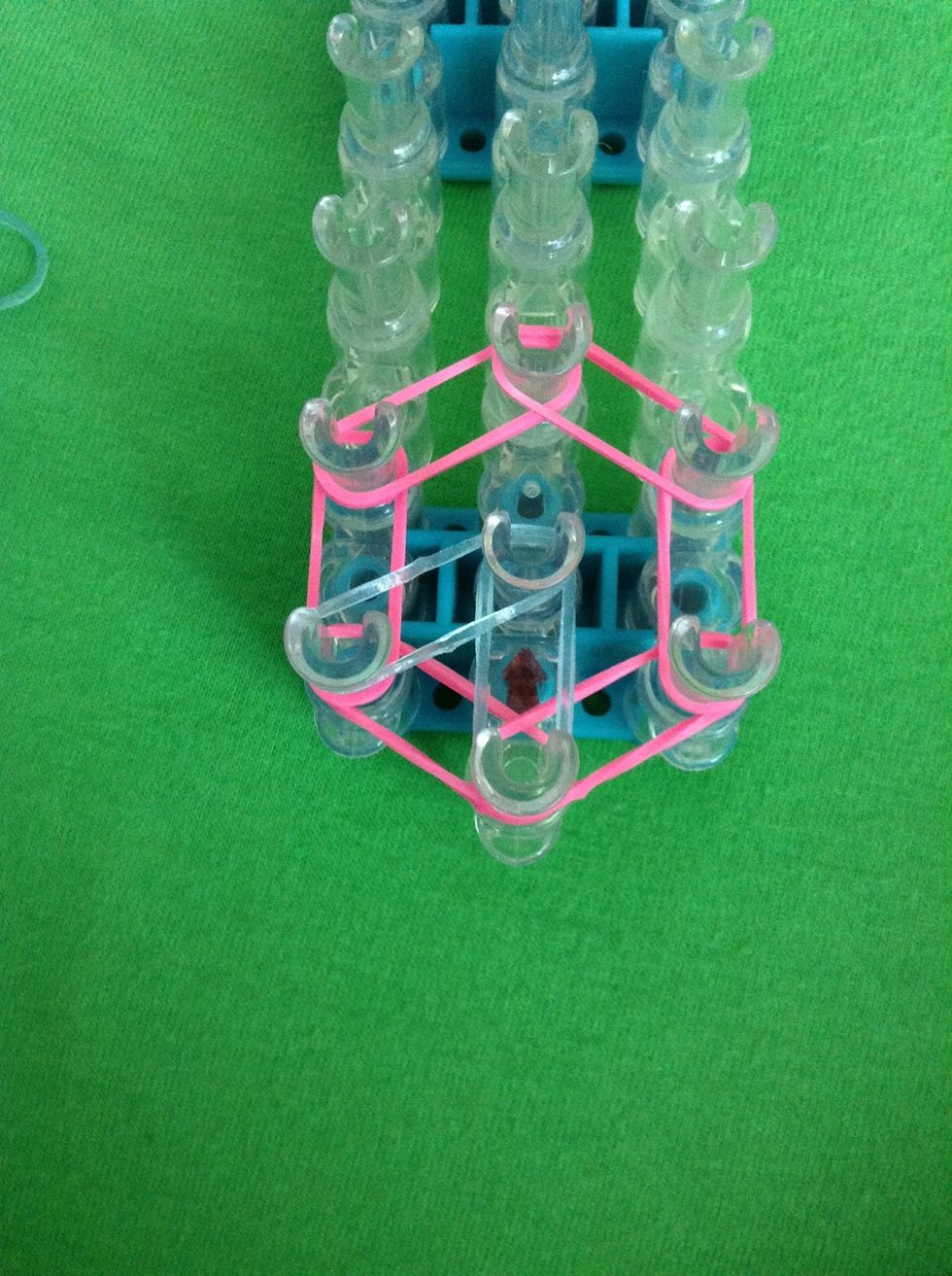 Stretch a rubber band from the first left peg to the center. Do this all the way around the flower