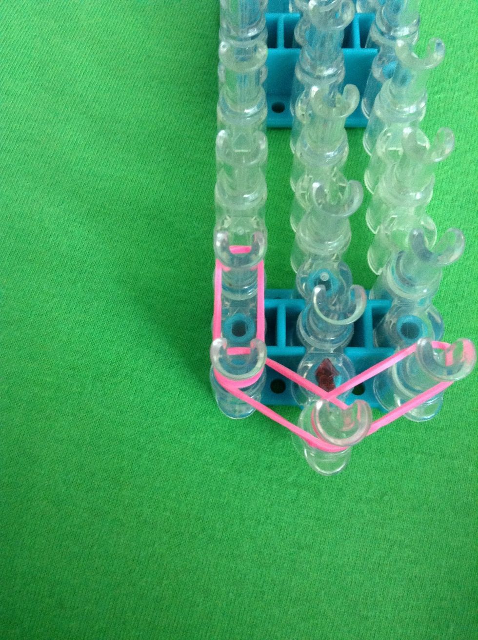 Stretch a rubber band from the left peg with part of the rubber band on it straight forward. Do this on the other side too