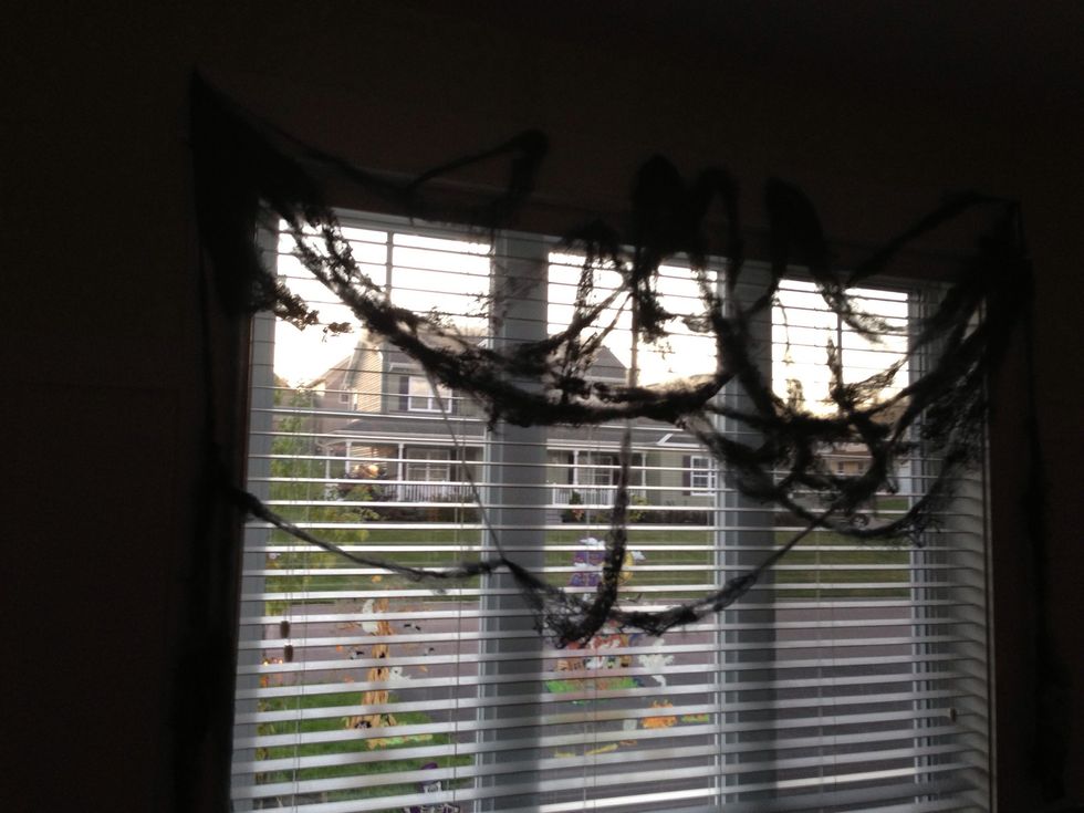 Stretch the black spider web from end to end of your window, starting from the top. Try to swag it from side to side repetitively, until all used, to create a gothic valance look and feel.
